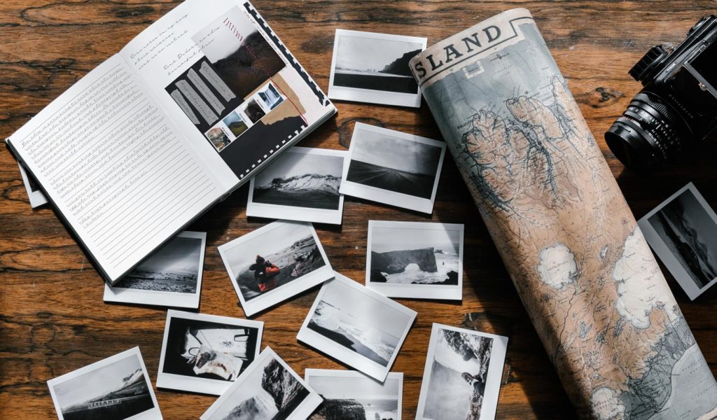 Travel journal with map, camera, and polaroids scattered on a table
